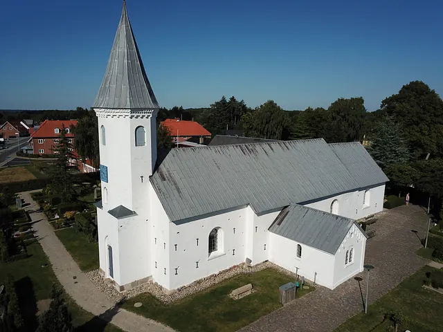 Hvid kirke med gråt tag og tårn som er Them kirke 
